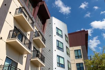 A modern building with balconies and a mix of white and darker colored panels.